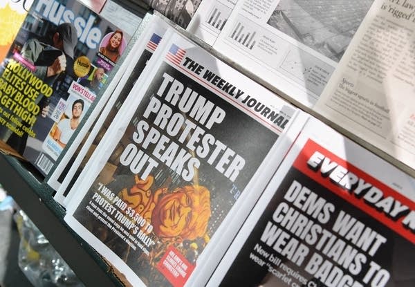 A newsstand shows publications with fake headlines.