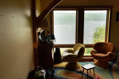 Bare walls where photos are usually hung are seen in a living room overlooking a lake.