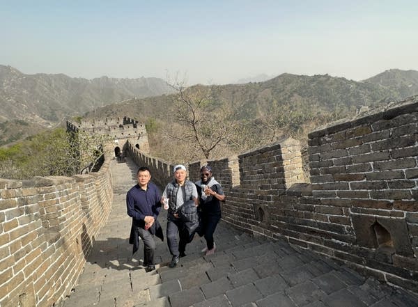 A photo of three men posing at the Great Wall of China.