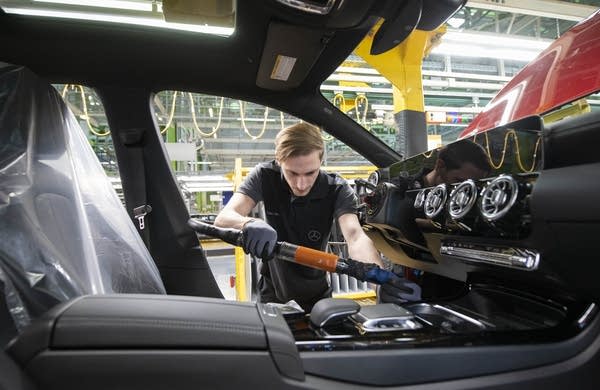 An employee works in the cockpit of a Mercedes Benz A Class on the assembly line at the Daimler AG factory in Rastatt, southwestern Germany, on February 4, 2019.  (Photo credit THOMAS KIENZLE/AFP/Getty Images)