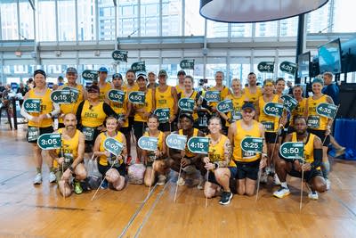 A group of pacer runners holding pace signs pose for a photo in a gymnasium.