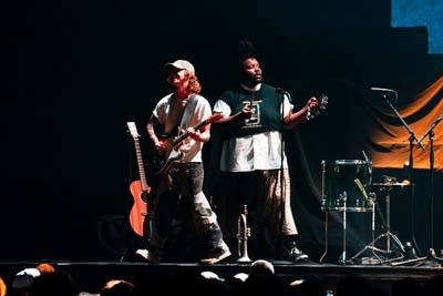 Two musicians performing onstage in a large arena