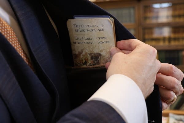 Close-up of a man pulling a pamphlet out of his breast pocket.