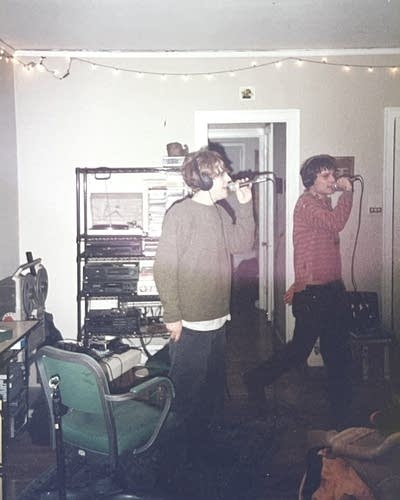 Two men play music in an apartment living room.