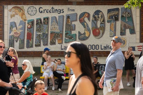 fairgoers walking in front of greetings from minnesota sign