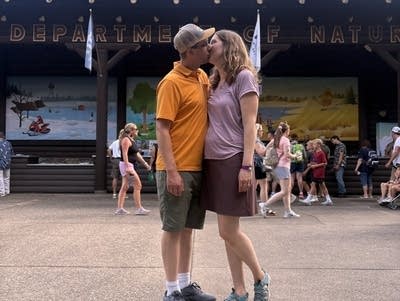 A couple kisses in front of a building