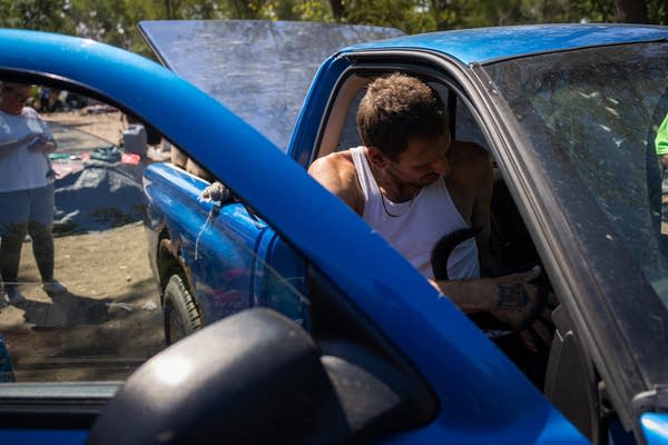 A man gets into a blue pickup truck