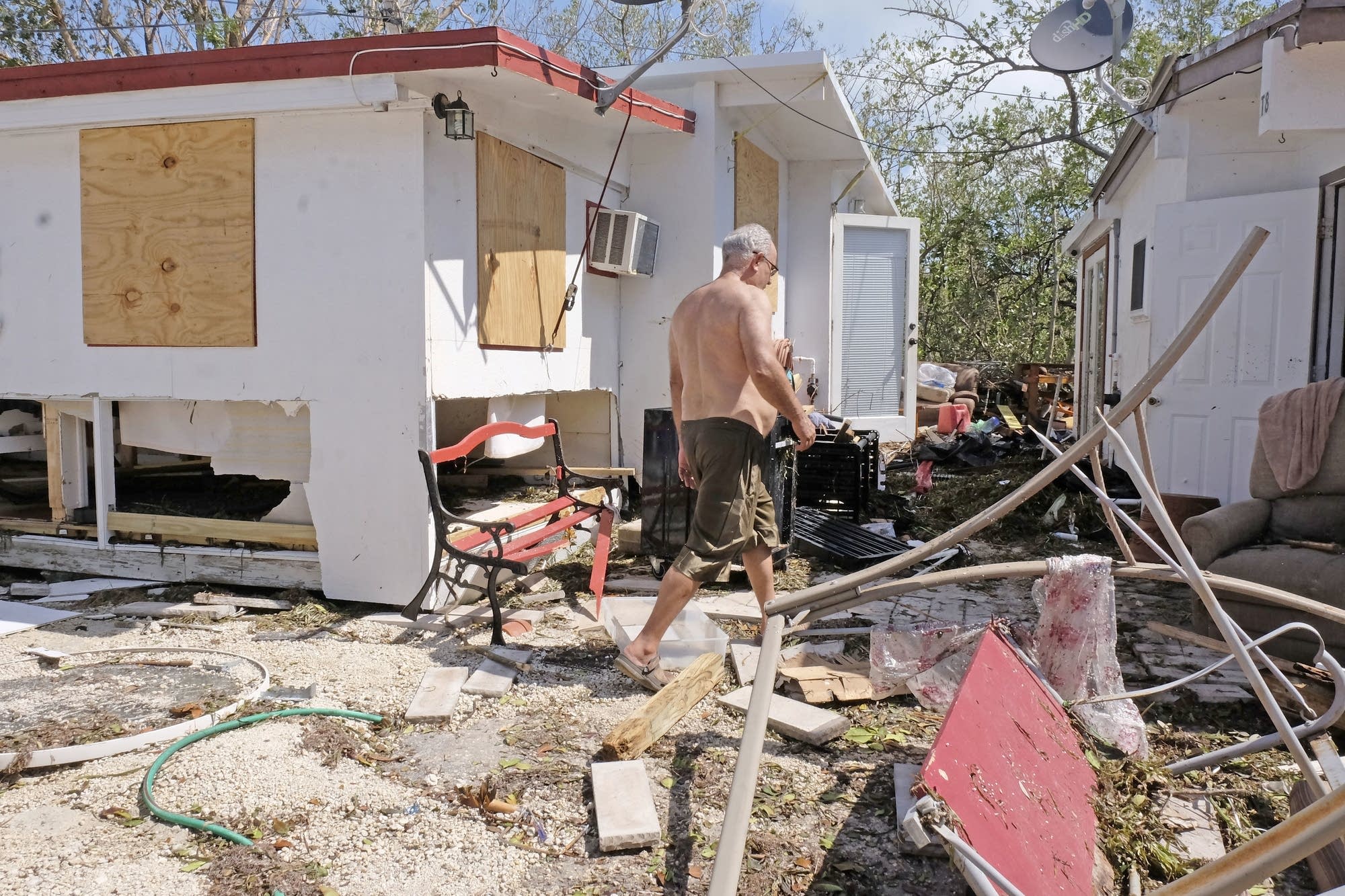 Gullermo Tejera, walks among the damage to his mobile home.