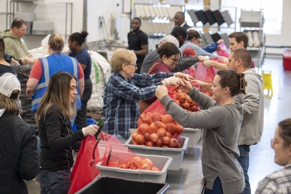 volunteers pack food donation boxes on an assembly line