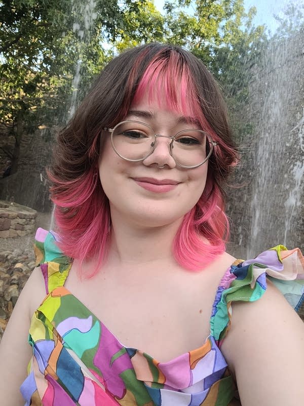 a person with colorful hair smiles