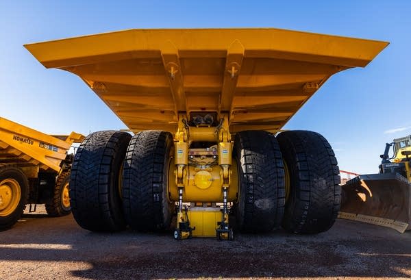 The undercarriage of a massive, yellow construction hauler.