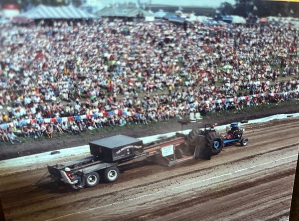A tractor pull with a large crowd watching.