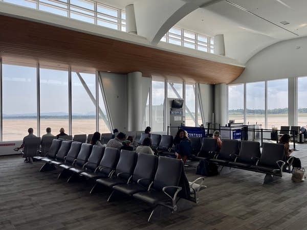 Passengers wait for a flight in an airport concourse.