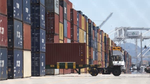 A truck drives by stacks of shipping containers at the Port of Oakland on May 20.