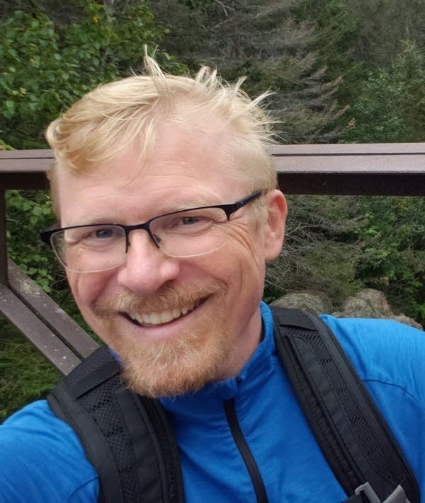 A man takes a selfie while hiking.