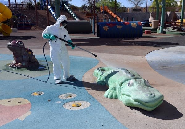 A worker pressure washes playground equipment at a park on March 25, 2020, in Las Vegas. 