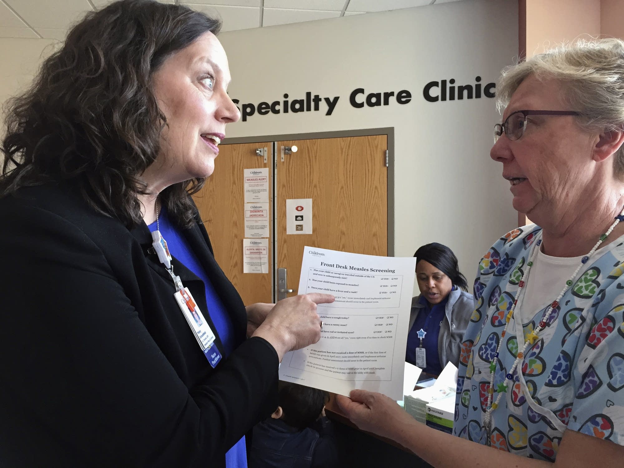 Patsy Stinchfield talks with nurse Kathy Kaul about a measles questionnaire