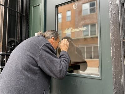 A man cups his hands to see through a door window.