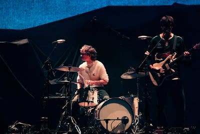 Two musicians performing onstage in a large arena