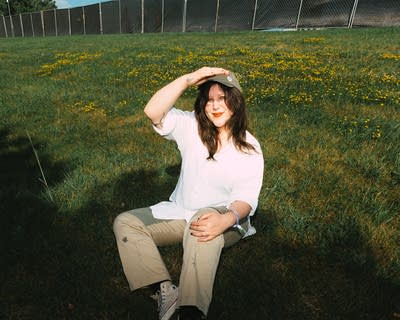 Lucy Dacus sitting on grass and posing for a photo