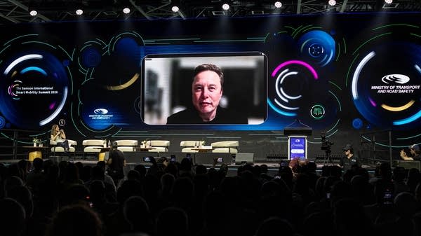 Elon Musk is seen on a large screen at the Smart Mobility Summit 2026 in Tel Aviv. His company SpaceX recently filed for an IPO.