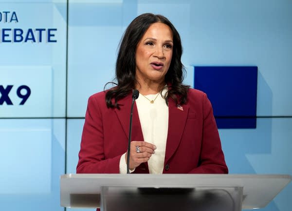a woman in red speaks at a podium