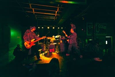 A three-person band performing onstage in a music venue