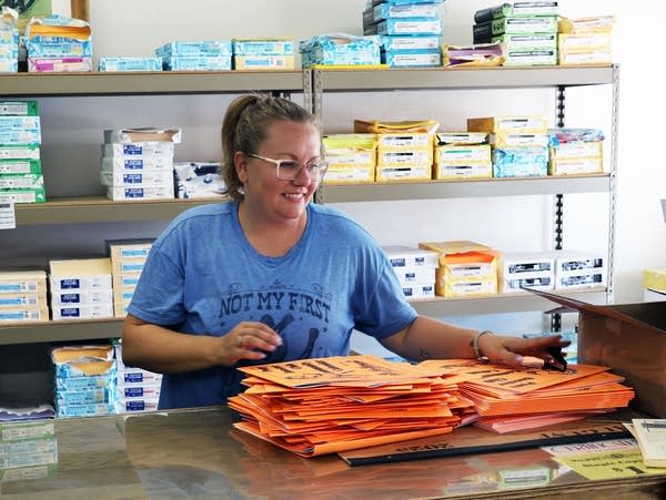 A woman in a blue shirt behind a wooden counter