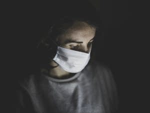 A woman wears a face mask in the dark.