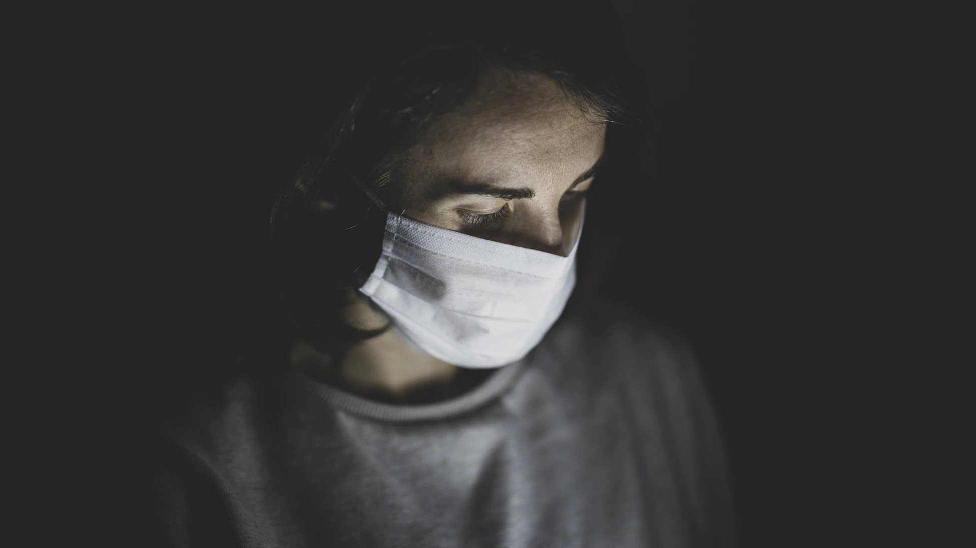 A woman wears a face mask in the dark.