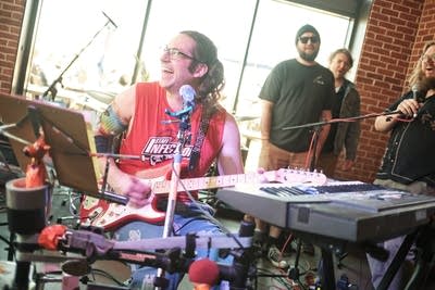 A musician plays several instruments simultaneously in a taproom
