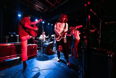 A five-piece band performing onstage in a music venue