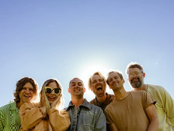 Six members of the Head and the Heart with blue sky behind.