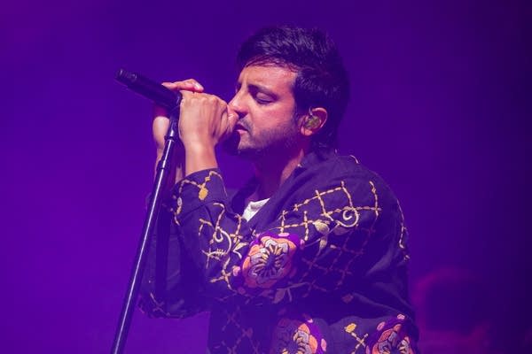 A man sings into a microphone onstage