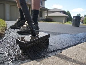 A coal tar-based sealant is applied on a driveway.