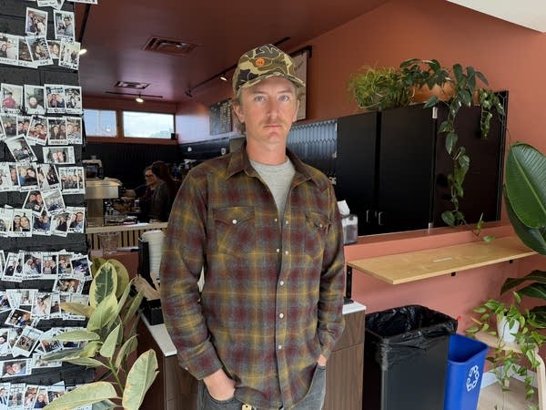 A man stands in a storefront to pose for a photograph.