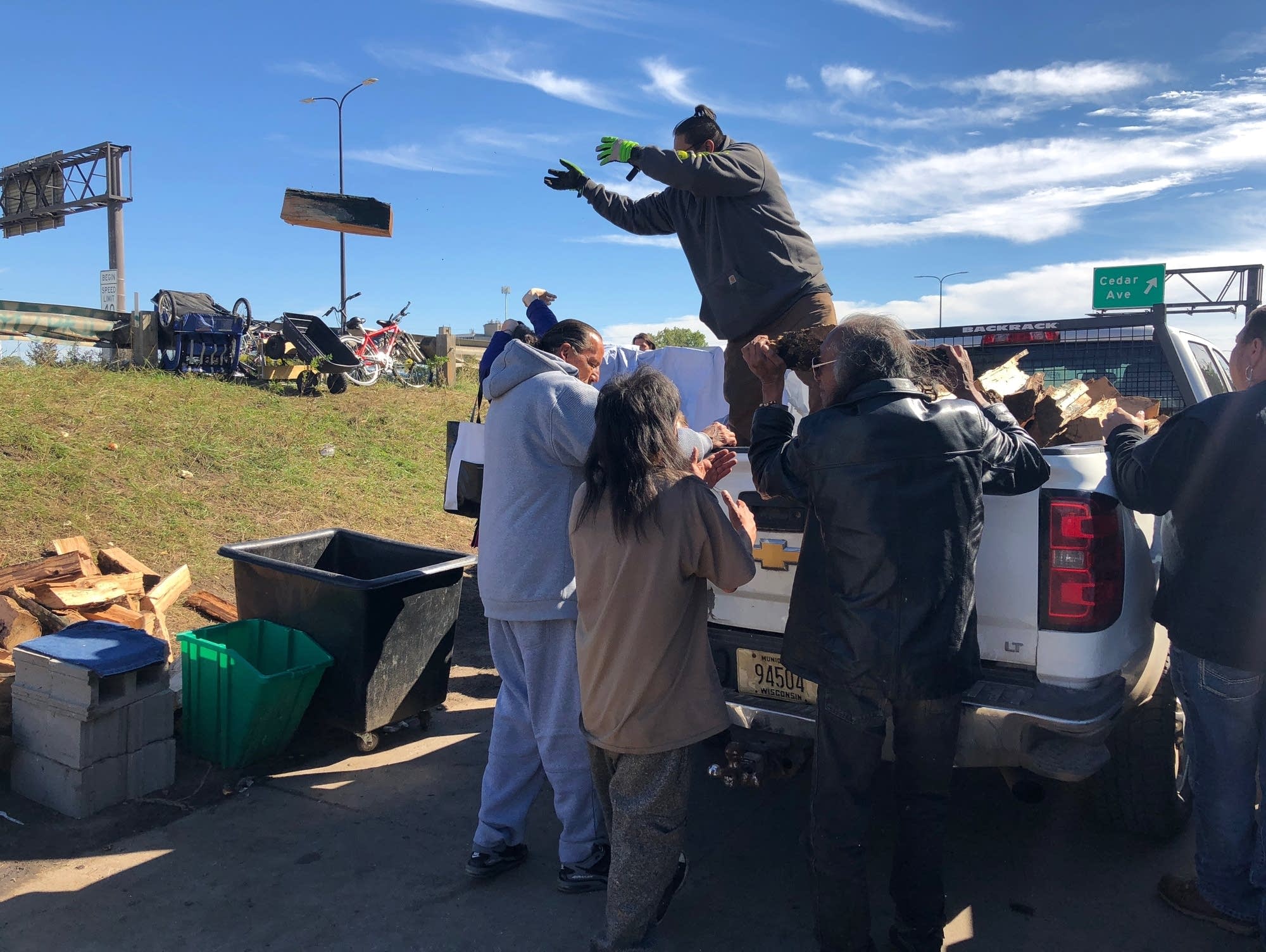 Volunteers and camp residents stack wood.