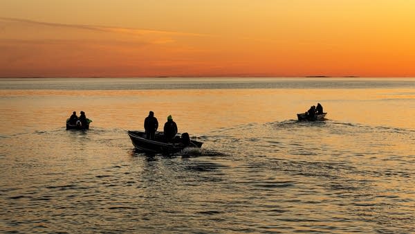 Fishing boats on a lake at sunset.