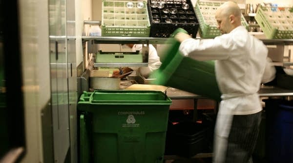 A cook at MoMo's restaurant in San Francisco, California empties food scraps into a larger recycling container.