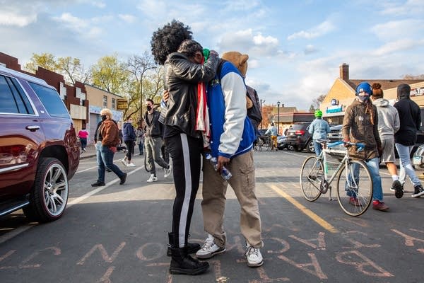 Two people hug in the middle of a street.