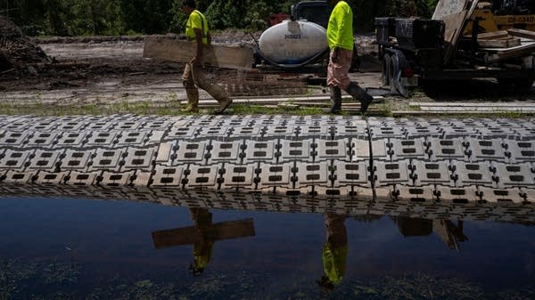 Workers improve a drain in a Central Florida region affected by flooding during Hurricane Ian. 