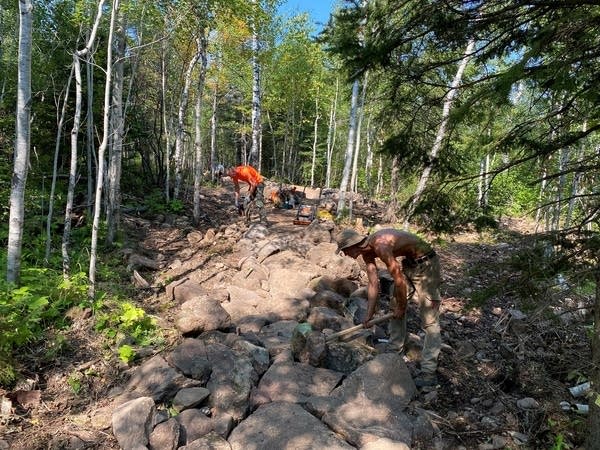 Two people build a mountain bike trail.