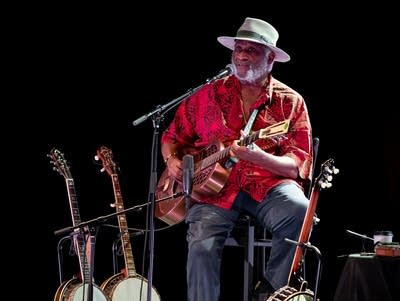 A man sings and plays a resonator guitar onstage