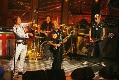 Four musicians performing together on a television soundstage