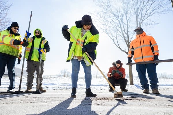 A crew in hi-vis gear fixes a pothole.