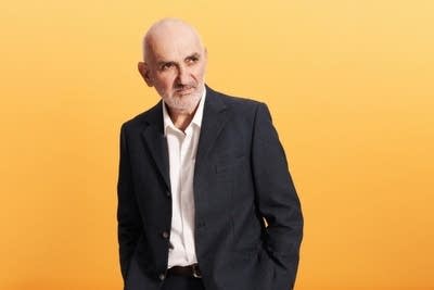 A man in a blazer poses for a studio portrait