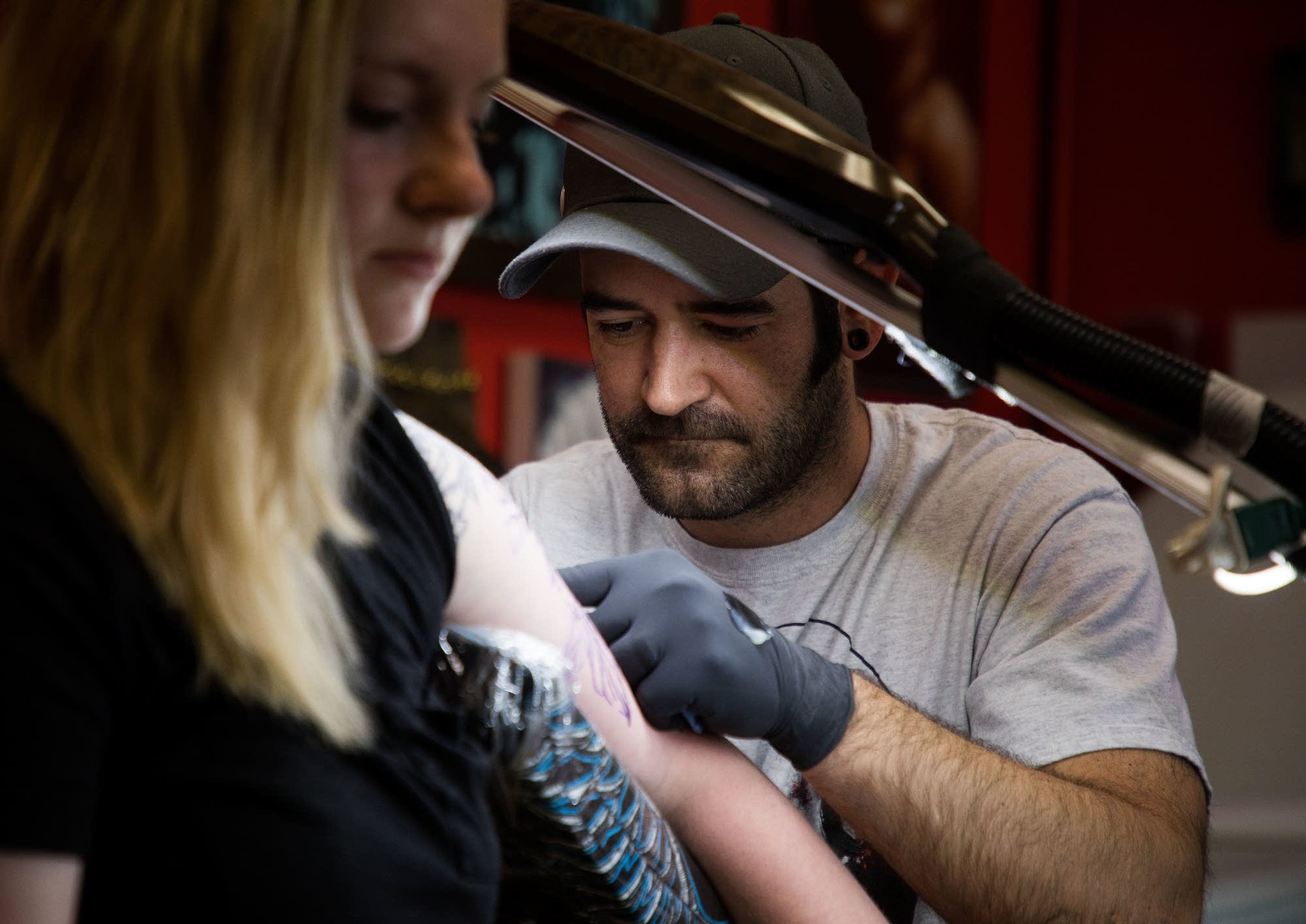 Jason Routley works on a new tattoo for Tailyn Bennett