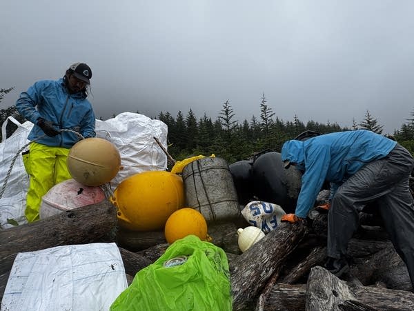 Two men help clean up a beach.