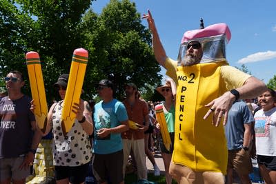 A man dances while wearing a pencil costume.
