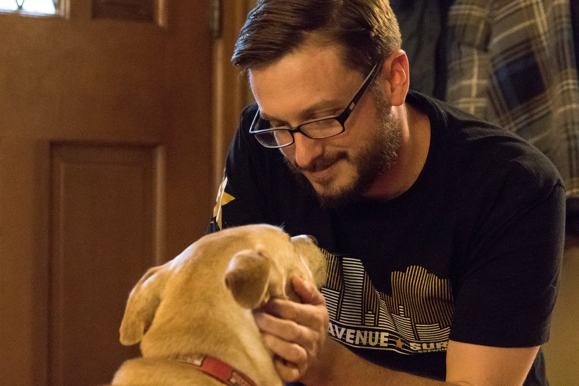 Mike Liay pets his dog Archie in his living room in Northeast Minneapolis.
